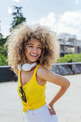 Glückliche Afro-Frau, die wegschaut, während sie mit der Hand in der Tasche steht - PGF00643