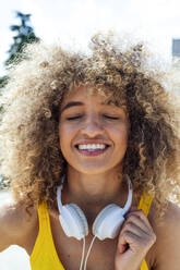 Smiling curly haired woman with eyes closed - PGF00646