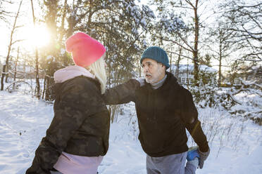 Couple exercising together while stretching on snow - FVDF00288
