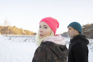 Frau schaut über die Schulter, während sie im Winter neben einem Mann steht - FVDF00294