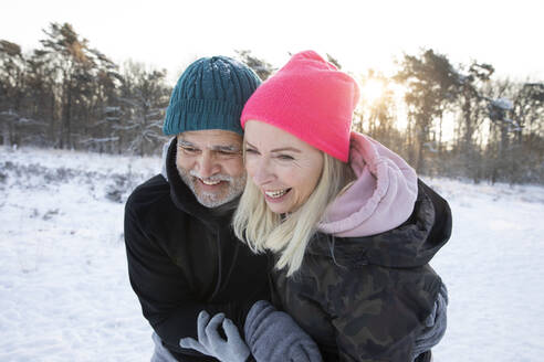 Lächelnder Mann umarmt Frau im Winter - FVDF00300