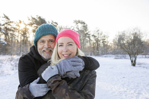 Lächelnder älterer Mann, der im Winter den Arm um eine Frau legt - FVDF00306