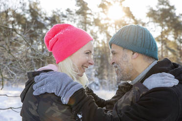 Happy senior couple wearing knit hats looking at each other - FVDF00329