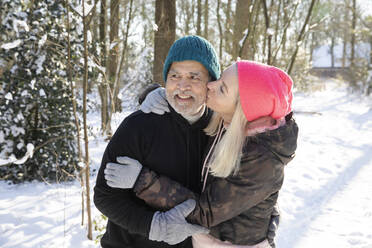 Frau küsst Mann im Wald im Winter - FVDF00337