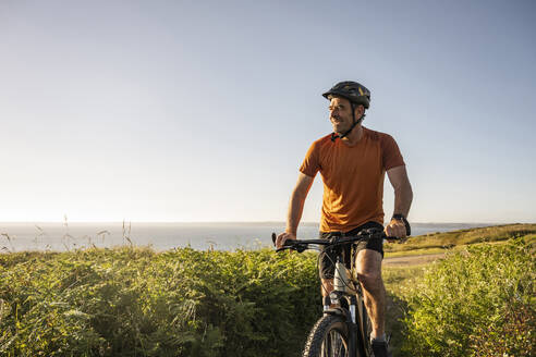Älterer Sportler fährt elektrisches Mountainbike bei Sonnenuntergang - UUF23738