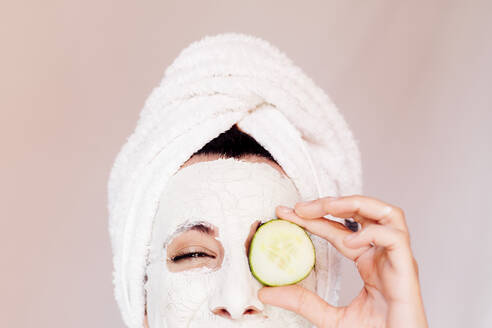 Young woman with beauty face mask covering eye with cucumber slice - EGHF00061