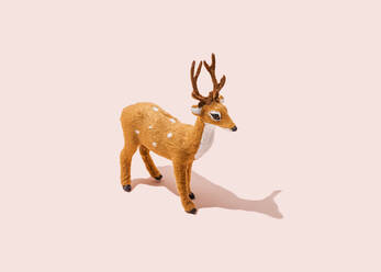 Studio shot of reindeer figurine standing against pink background - FLMF00528