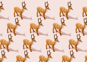 Pattern of reindeer figurines standing against pink background - FLMF00529