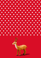 Studio shot of reindeer figurine standing against vibrant red polka dot background - FLMF00532
