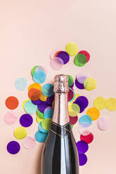 Studio Schuss von Flasche Champagner und bunten Konfetti gegen Pastell rosa Hintergrund liegen - FLMF00538