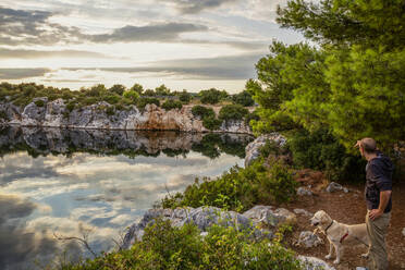 Man and dog looking at Lake Dragon's Eye during vacation, Rogoznica, Croatia - MAMF01895