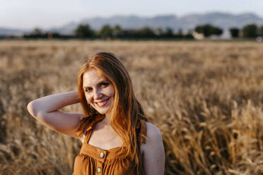 Smiling redhead woman in agricultural field - TCEF01977