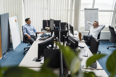 Männliche Kollegen sitzen am Schreibtisch im Büro - DIGF15952