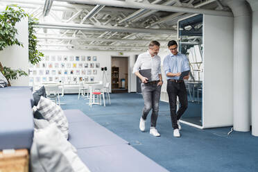 Männliche Berufstätige diskutieren bei der Nutzung eines digitalen Tablets im Büro - DIGF15958