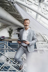 Male professional holding digital tablet while leaning on railing - DIGF15982