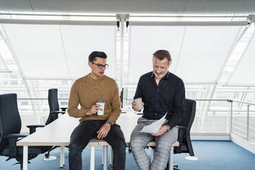 Männliche Kollegen mit Kaffeetasse bei der Arbeit am Schreibtisch - DIGF15996