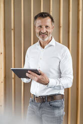 Männlicher Fachmann mit digitalem Tablet vor einer Wand stehend - DIGF16035