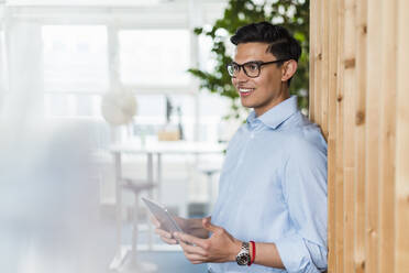 Smiling male professional holding digital tablet in office - DIGF16044