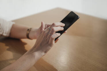 Woman using mobile phone at table in cafe - EBBF04110