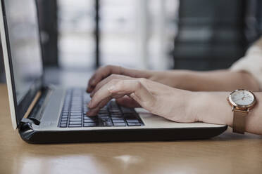 Hands of female freelancer typing on laptop in cafe - EBBF04114