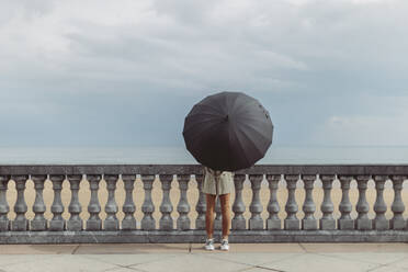 Frau mit Regenschirm auf der Promenade stehend - MTBF01046