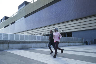 Couple running on footpath in city - PMF01936