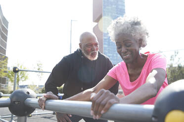 Man looking at woman exercising in park - PMF01944