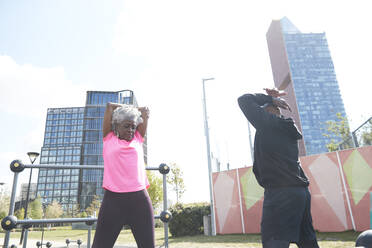 Couple stretching while exercising together at park - PMF01950