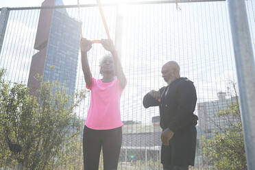 Man checking time by woman exercising with resistance band at park - PMF01964