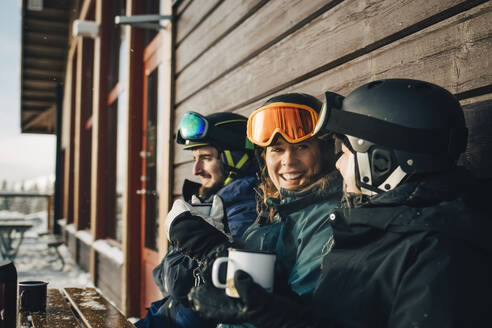 Happy male and female friends spending leisure time while having coffee at ski resort - MASF24309