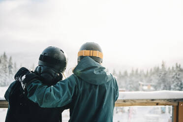 Rückansicht von Freundinnen, die sich über ein Geländer im Skigebiet lehnen - MASF24312