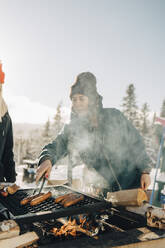 Freundinnen bereiten im Winter Würstchen auf dem Grill zu - MASF24324