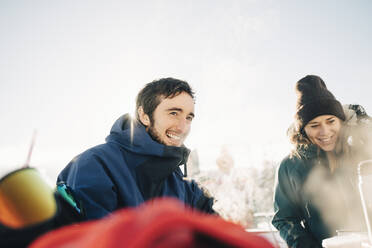 Lächelnde männliche und weibliche Freunde, die sich im Skigebiet vergnügen - MASF24325