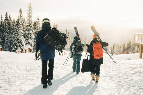 Rückansicht in voller Länge von Freunden, die im Winter im Skigebiet spazieren gehen - MASF24332