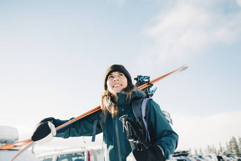 Lächelnde Frau mit Skiern im Winter gegen den Himmel - MASF24337