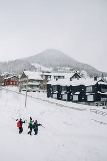Männliche und weibliche Freunde gehen im Winter im Skigebiet im Schnee spazieren - MASF24370