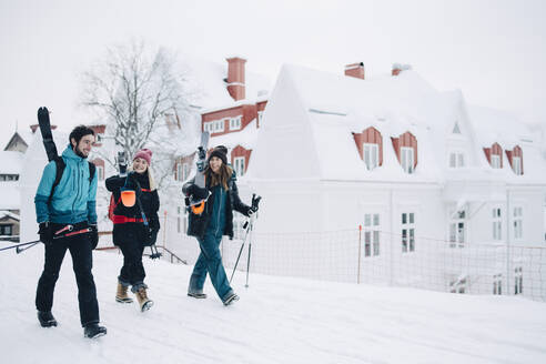 In voller Länge von weiblichen und männlichen Freunden, die miteinander reden, während sie auf Schnee gehen - MASF24373