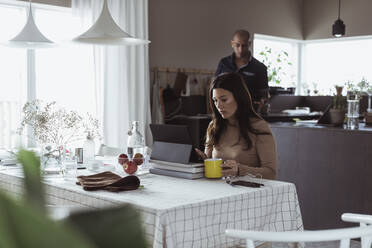 Berufstätige Frau arbeitet zu Hause an einem digitalen Tablet - MASF24393