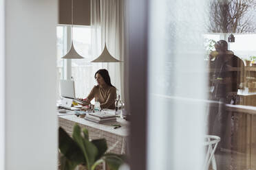 Female professional working on laptop at home office - MASF24399