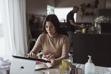 Female entrepreneur working on digital tablet at home - MASF24406