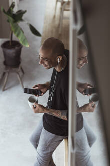 Hoher Blickwinkel eines Mannes, der mit einem Mobiltelefon spricht, während er eine Kaffeetasse zu Hause hält - MASF24413