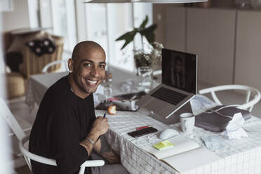 Porträt eines lächelnden Geschäftsmannes bei einem Videogespräch über Laptop während der COVID-19 - MASF24425
