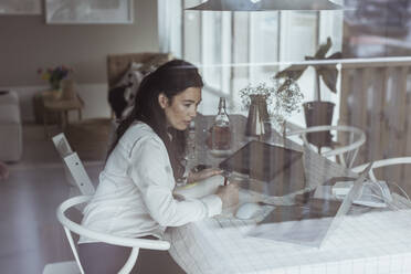 Berufstätige Frau schreibt bei der Arbeit zu Hause in ihr Tagebuch - MASF24444