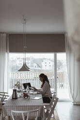 Businesswoman working on laptop at home office - MASF24445