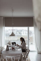 Geschäftsfrau arbeitet am Laptop im Büro zu Hause - MASF24445