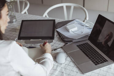 Businesswoman on meeting through video call with male colleague at home office - MASF24446