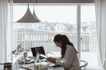 Lächelnde Geschäftsfrau bei einem Videogespräch mit einem männlichen Kollegen im Home Office während einer Pandemie - MASF24447