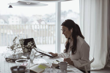 Smiling businesswoman using digital tablet at home office - MASF24450