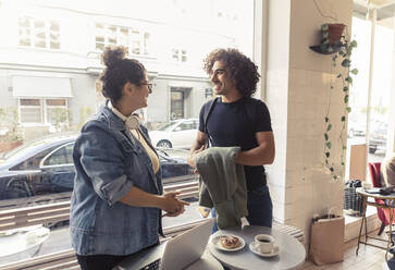 Glückliche männliche und weibliche Freunde unterhalten sich in einem Café - MASF24471