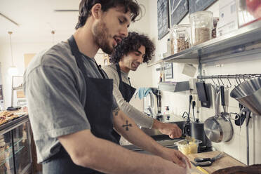 Männliche Unternehmer diskutieren bei der gemeinsamen Arbeit in einem Café - MASF24488